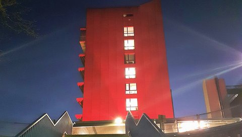 Das Hauptgebäude der MHH wird zum Weltenzephalitistag rot angeleuchtet.