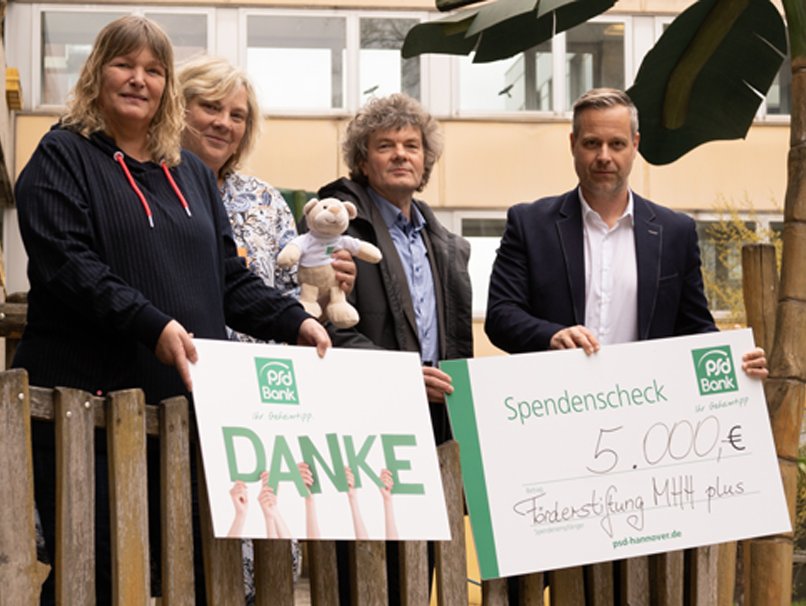 Vier Menschen stehen für die Übergabe des Spendenschecks auf einem Spielschiff im Innenhof der Kinderklinik.