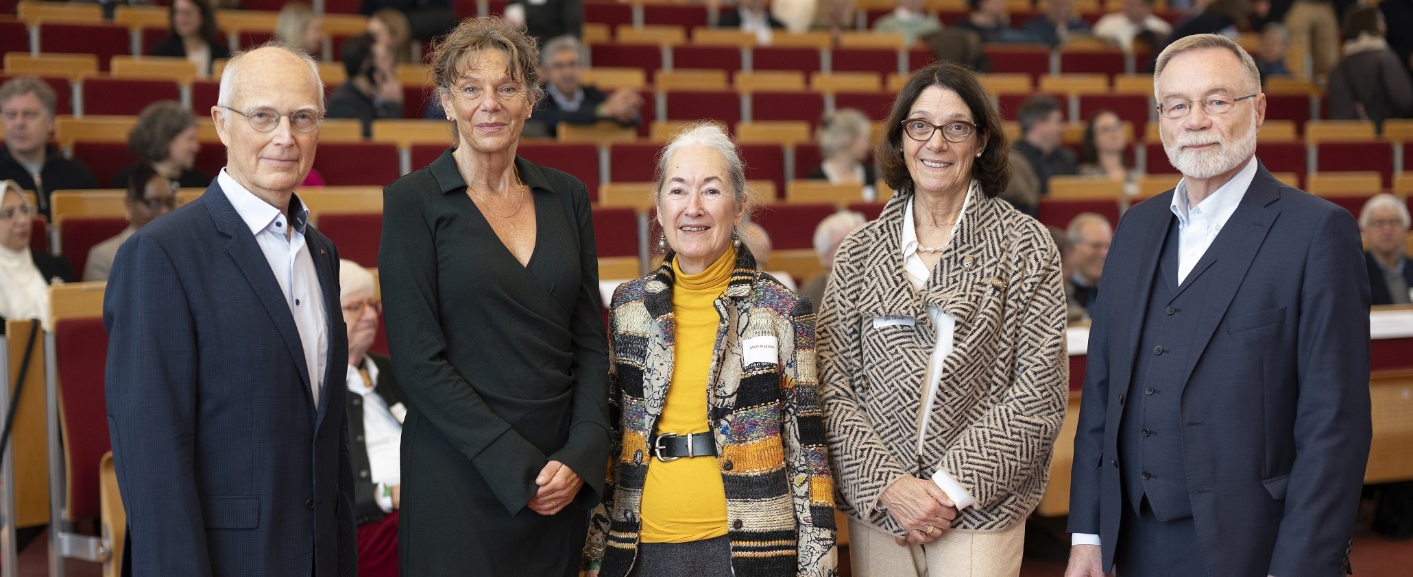 Der ehemalige Alumni-Vorsitzende Prof. Dr. Siegfried Piepenbrock (li.) und sein Nachfolger im Amt Prof. Dr. Ingo Just (re.), in der Mitte MHH-Präsidentin Prof. Denise Hilfiker-Kleiner, Alumni-Urgestein Almuth Bredimus und Dr. Marion Renneberg, stv. Präsidentin der Ärztekammer Niedersachsen (v.l.) stehe nebeneinander in einem Hörsaal. 