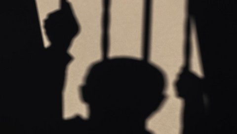 Ein Schattenbild zeigt einen menschlichen Kopf hinter Gittern.
