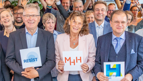 Mehrere Personen stehen zusammen und lächeln in die Kamera.