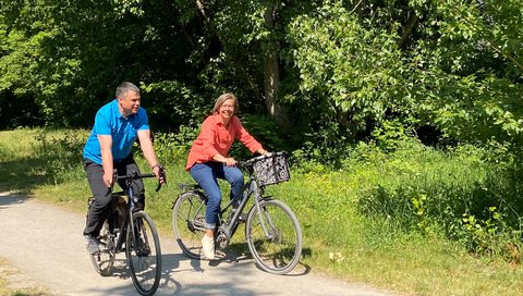 two persons on bikes riding through a green park