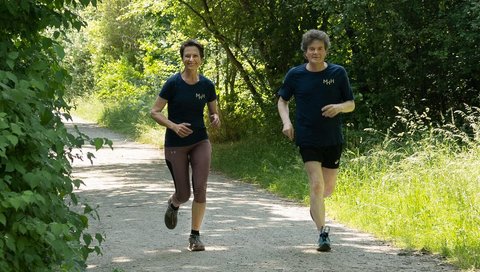 MHH-Vizepräsidentin Martina Saurin und Dr. Eckhard Schenke, Vorstand der Förderstiftung, joggen gemeinsam einen Waldweg entlang.