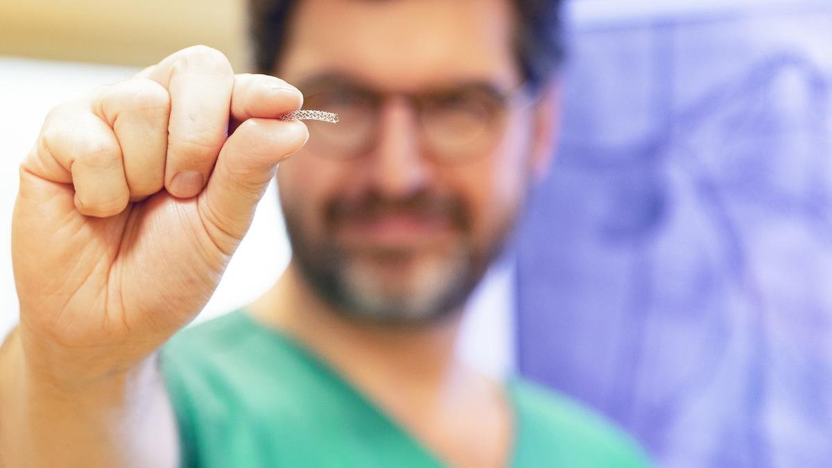 One hand holds the new absorbable stent.