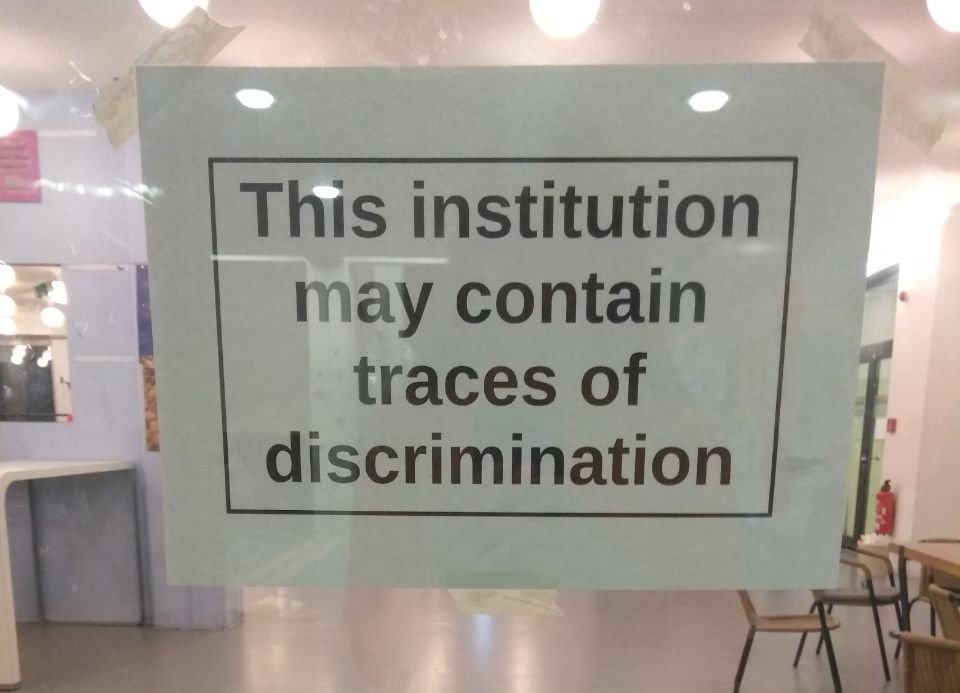 Foto von Zettel hinter Glastür: This institution may contain traces of discrimination