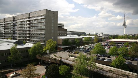 Blick von oben auf das zentrale Bettenhaus mit Parkdeck und umliegenden Gebäuden. 