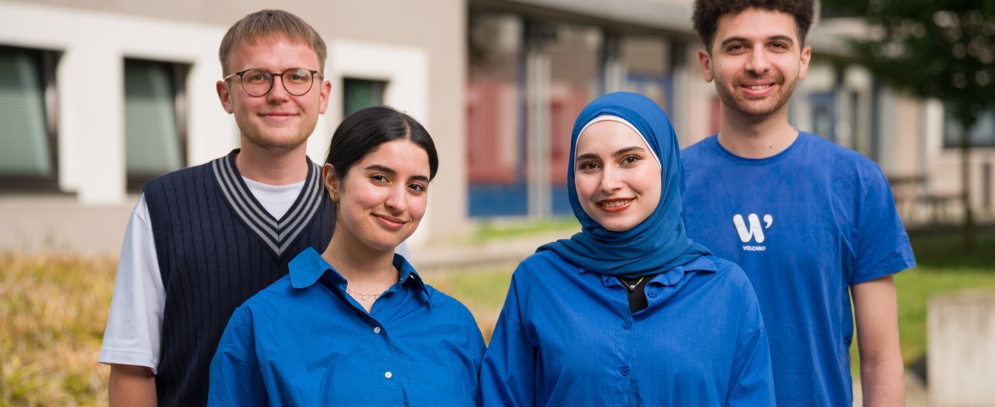 Vier Personen stehen für ein Gruppenbild zusammen. 