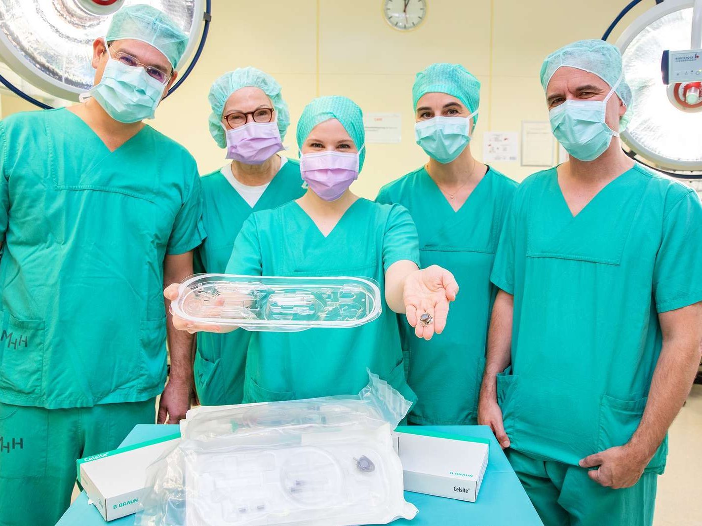 Five doctors in green surgical gowns stand side by side and show the port system.