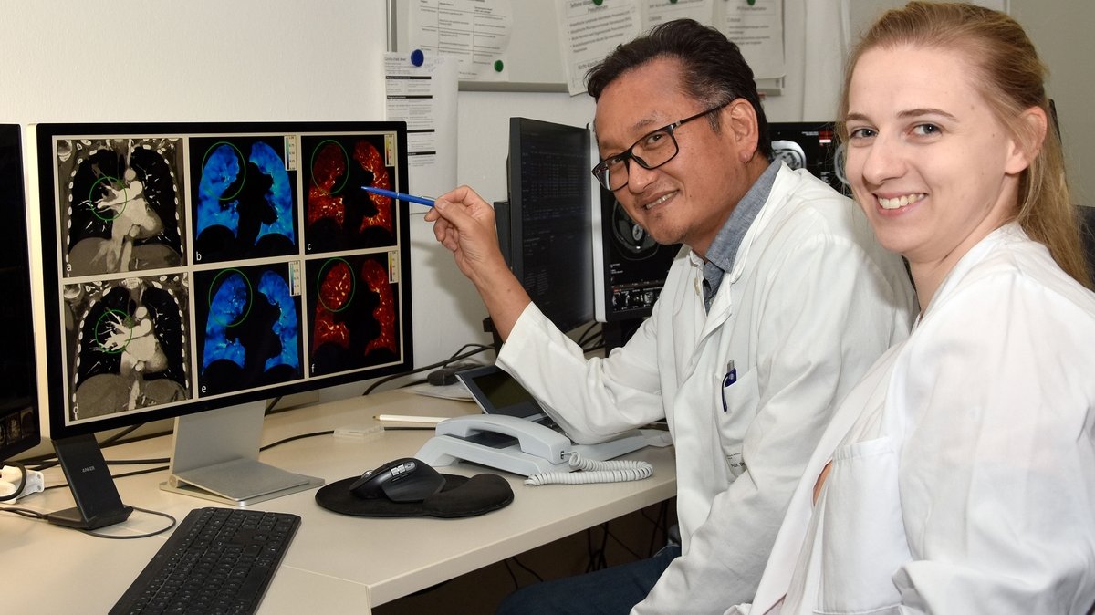 Das Foto zeigt einen Arzt und eine Ärztin, die am Bildschirm die CT-Aufnahmen einer Lunge betrachten. Struktur, Belüftung und Durchblutung des Organs sind jeweils in andern Farben dargestellt. 