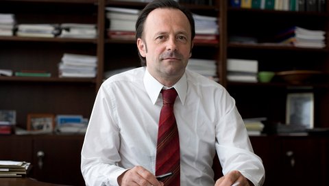 Prof. Dr. med. Joachim K. Krauss sitzt in seinem Büro an einem Schreibtisch. 