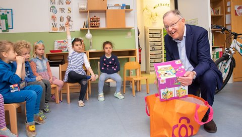 Der Niedersächsische Ministerpräsident Stephan Weil hat bei seinem Besuch in der MHH-Kita Campuskinder Spielzeuggeschenke mitgebracht und übergibt sie den Kindern.