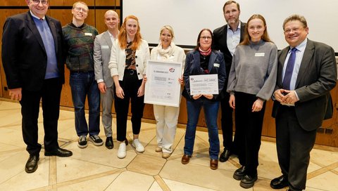 A group of people with a certificate on a stage.