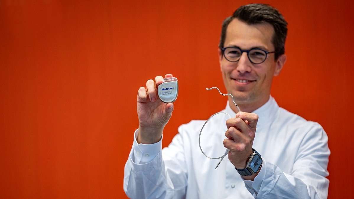 Professor Duncker holds the "Aurora" defibrillator and the corresponding electrode in his hands.