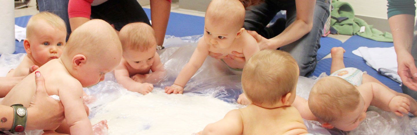 Babygruppe beim Spielen auf einer Matschunterlage