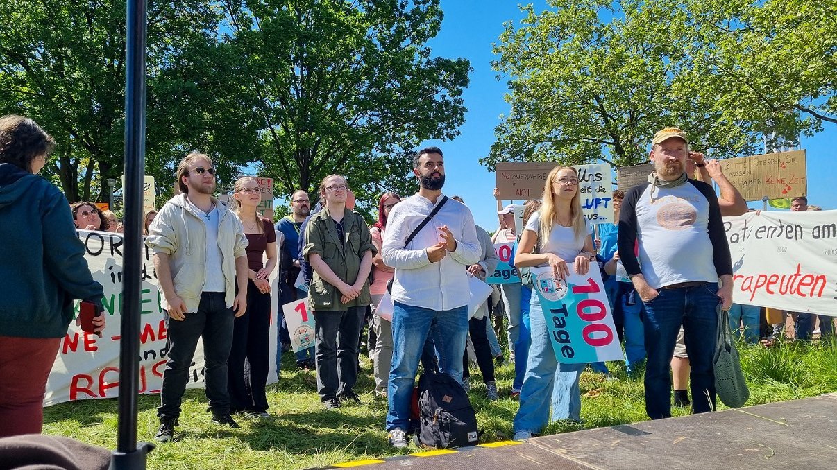 Mehrere Menschen stehen bei einer Kundgebung vor dem MHH-Campus. 