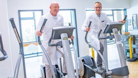Professor Dr. Uwe Tegtbur (left) and Professor Dr. Heiner Wedemeyer work out on cross trainers in the fitness room of MHH Sports Medicine.