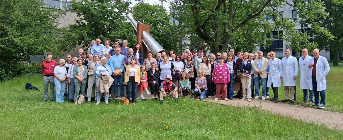 Eine große Gruppe aus Langzeit-Lebertransplantierten, Angehörigen und medizinischem Personal versammeln sich am DankeMal im Patientengarten der MHH – einem Ort des Gedenkens an die Organspenderinnen und Organspender.