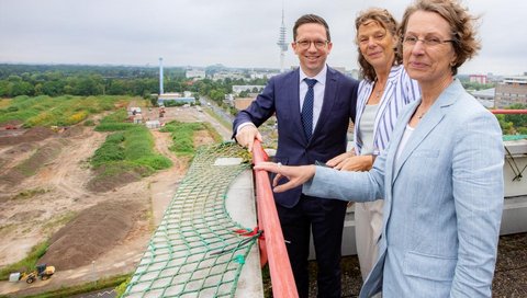 [Translate to Englisch:] Minister Mohrs, Denise Hilfiker-Kleiner und Martina Saurin blicken von oben auf das Neubaufeld. 