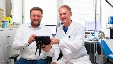 Dr. Matthias Gietzelt und Professor Bavendiek sitzen nebeneinander in einem kardiologischen Untersuchungsraum.