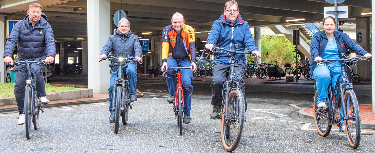 Fünf Personen fahren auf Fahrrädern auf einer Straße auf dem MHH-Campus