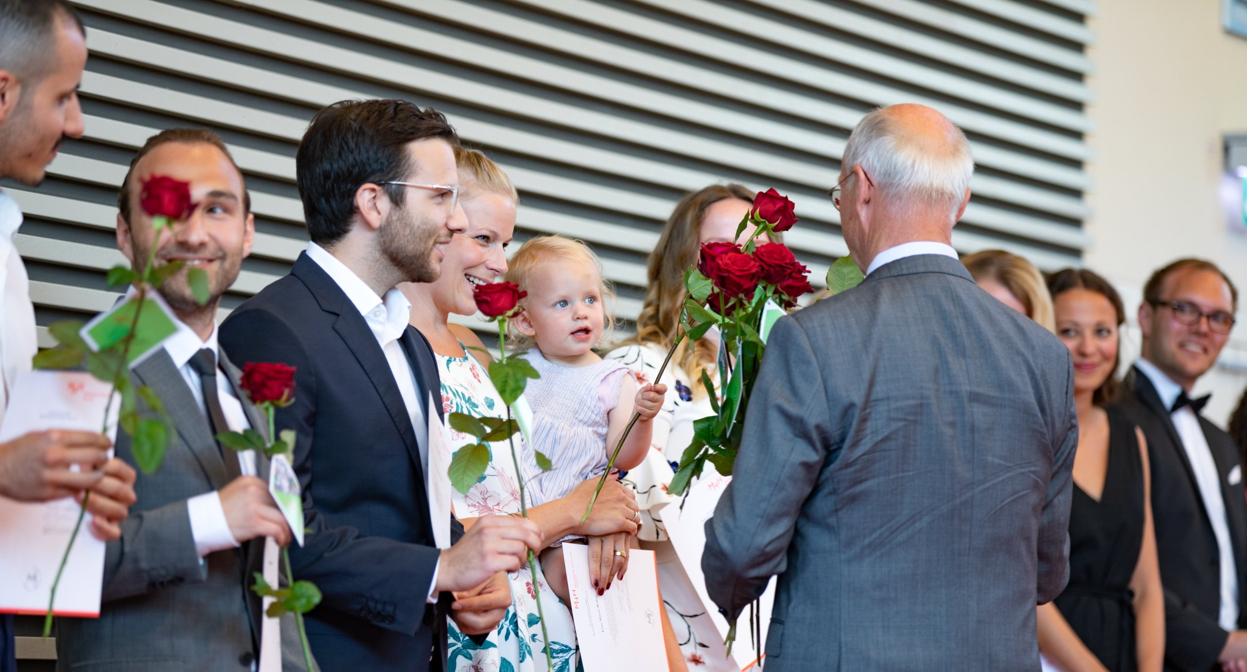 Absolventinnen und Absolventen werden mit roten Rosen verabschiedet.
