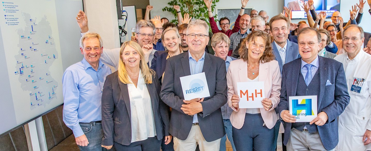  Mehrere Personen stehen zusammen und lächeln in die Kamera.