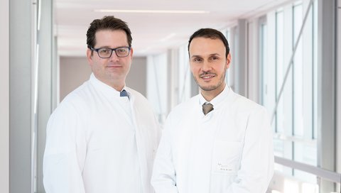PD Dr. Philipp Ivanyi und Prof. Dr. Mohamed Omar stehen in einem Flur der Medizinischen Hochschule Hannover.