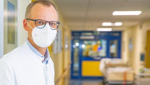 Prof. Wedemeyer auf einem Klinikflur, schaut in die Kamera.