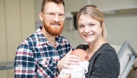 A newborn girl in the arms of her parents.