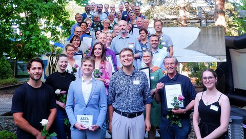 Mehrere Menschen stehen aufgereiht auf einer Treppe für ein Gruppenfoto zusammen. 