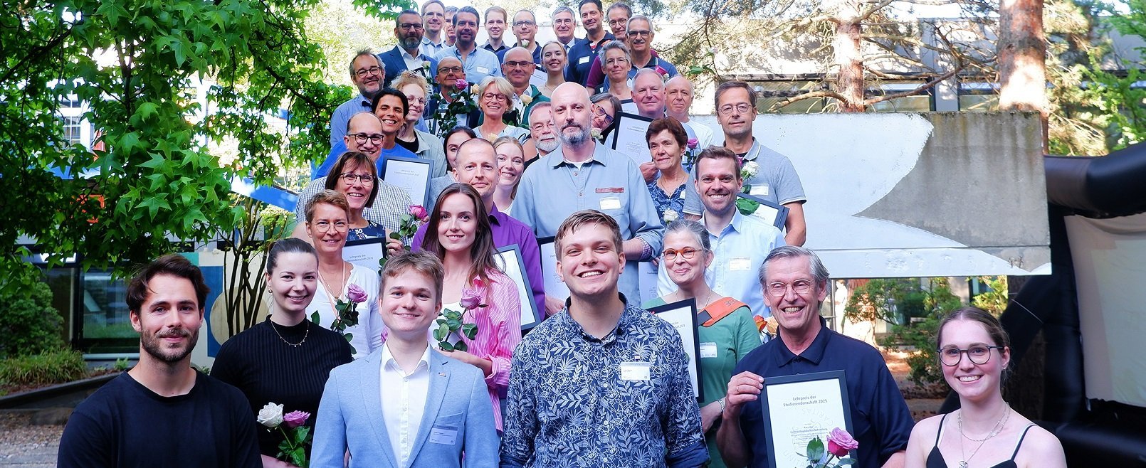 Mehrere Personen stehen für ein Gruppenfoto in Reihen auf einer Treppe. 