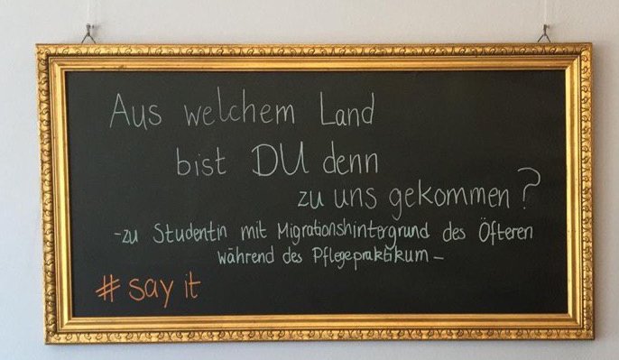 Goldenumrahmte Tafel mit der Aufschrift: "Aus welchem Land bist DU denn zu uns gekommen?" - zu Studenten mit Migrationshintergrund des Öfterne während des Pflegepraktikums