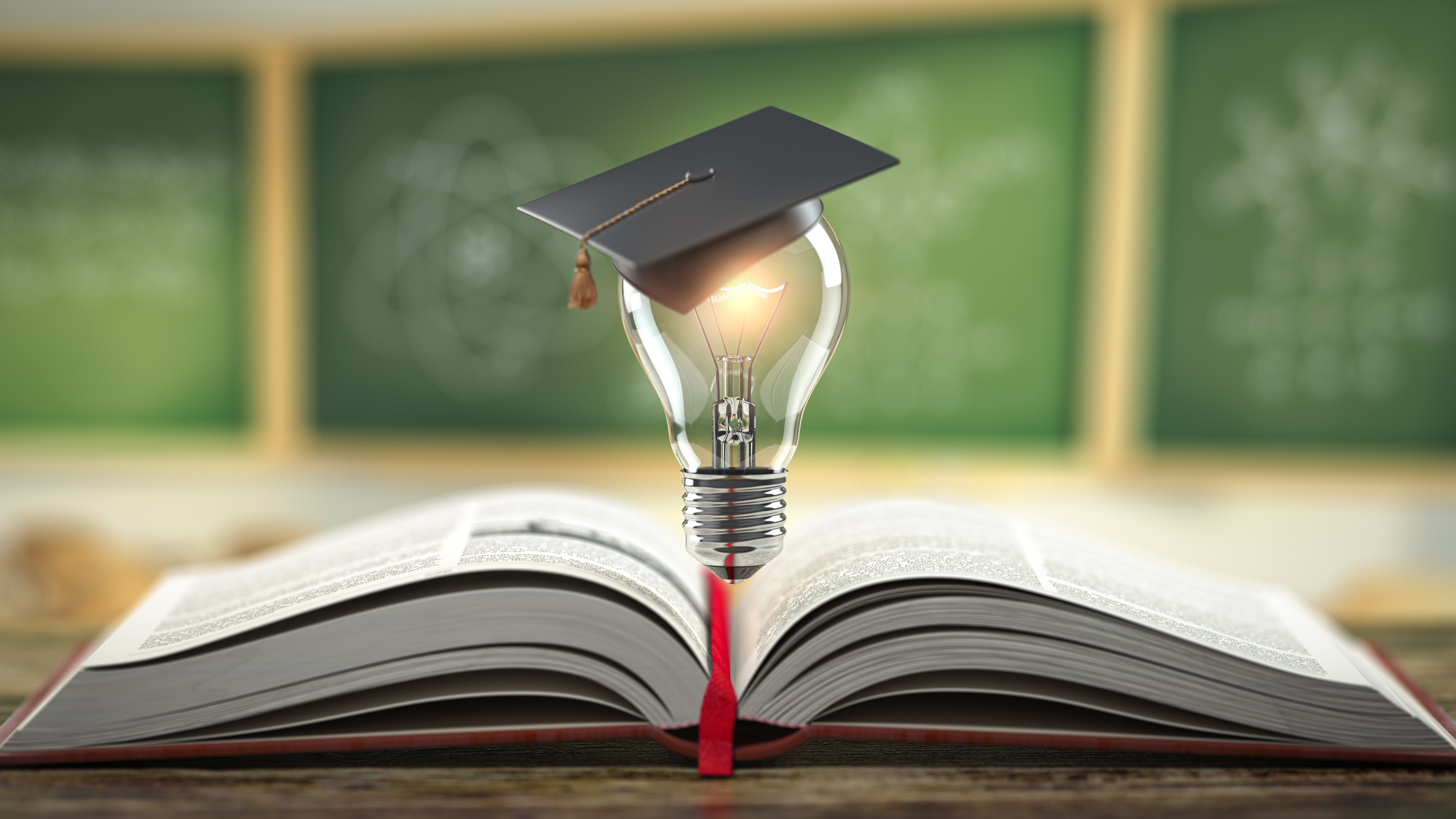 Im Vordergrund liegt ein aufgeschlagenes Buch mit rotem Einband und rotem Lesezeichen mittig aufgeschlagen auf einem Holztisch. Über dem Buch schwebt eine leuchtende Glühlampe, die einen Doktorhut trägt. Im Hintergrund ist eine drüne, dreiteilige Tafel verschwommen zu erkennen.