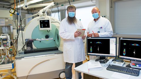 Dr. Jens Bankstahl und Professor Dr. Tobias Ross stehen neben einem Kombinationsgerät für präklinische Positronenemissionstomographie/Computertomographie (PET/CT)