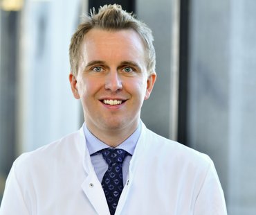 Porträtbild von Ingmar Mederacke, der einen weißen Arztkittel trägt. 