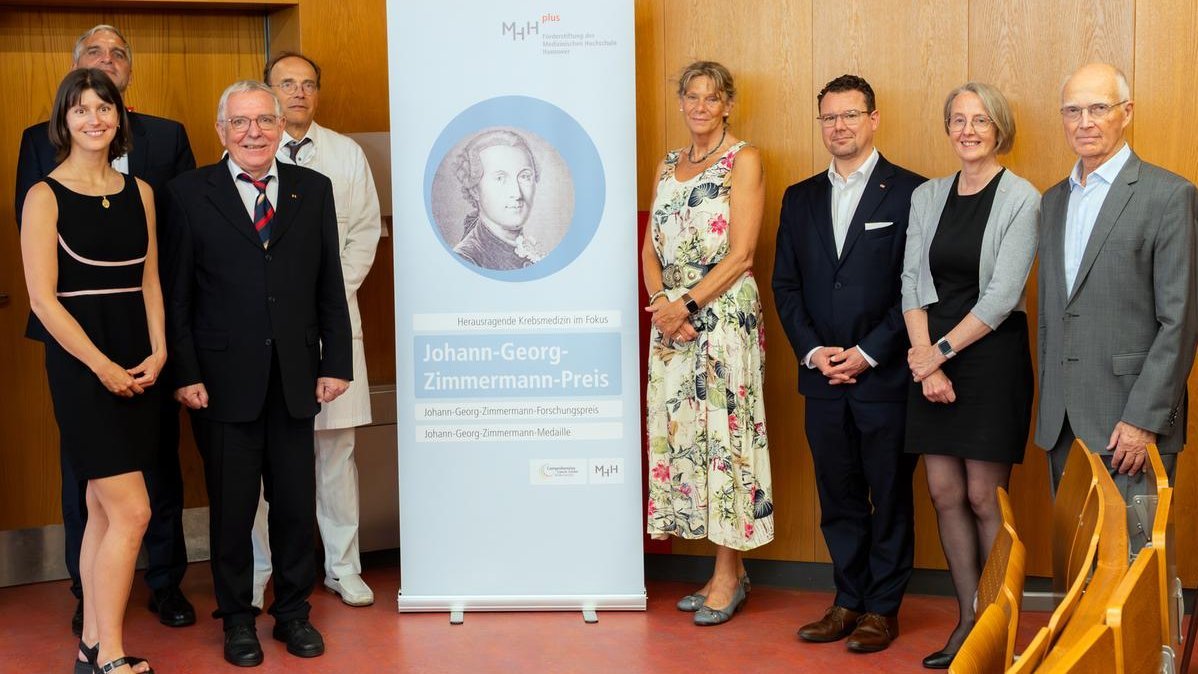 eine Gruppe Personen steht vor einem Banner
