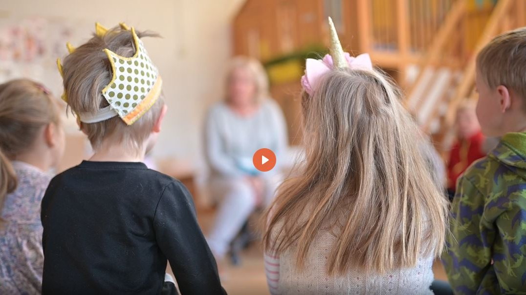 Kinder mit Papierkrone und Einhorn-Kostüm sitzen in der Kita Campus-Kinder in einem Stuhlkreis. 