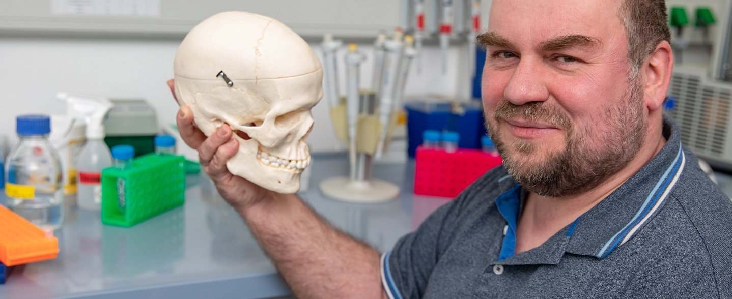 Prof. Dr. Christoph Garbers Mann hält das Modell eines menschlichen Schädels in den Händen.
