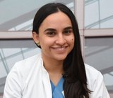 Porträtbild von Mayra Maldonado Lee, die einen weißen Arztkittel trägt. 