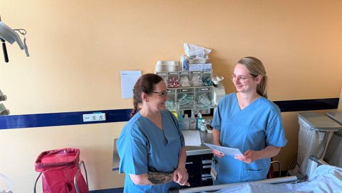 Zwei Pflegekräfte am Bett eines Patienten.