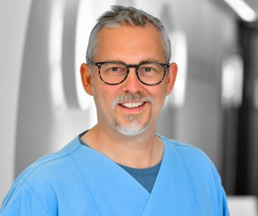 Porträtbild von Guntram Schwörer, der einen blauen Kasack trägt. 