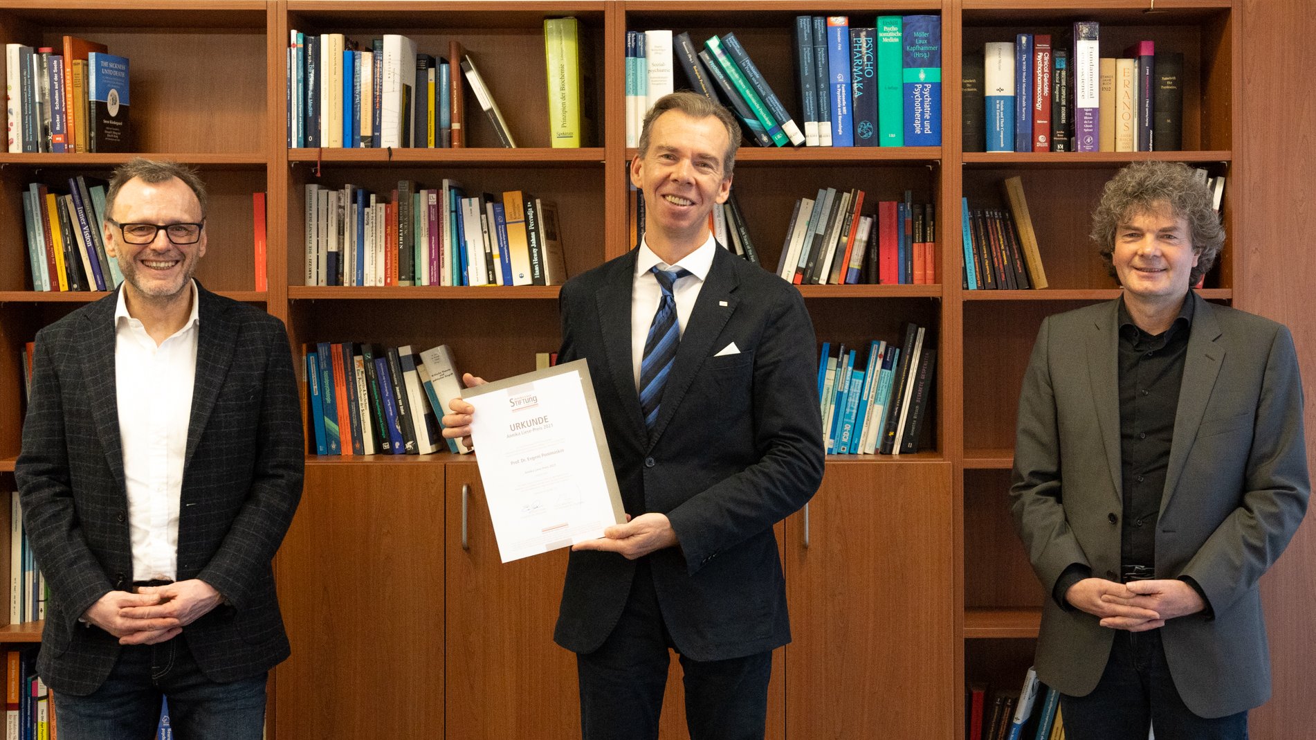 In der Bildmitte hält Preisträger Professor Ponimaskin seine Urkunde in die Kamera. Linkst steht Professor Kai G. Kahl, rechts Dr. Eckhard Schenke.