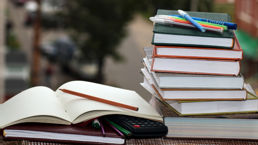 Aufgeschlagenes Buch neben Bücherstapel
