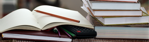 Aufgeschlagenes Buch neben Bücherstapel