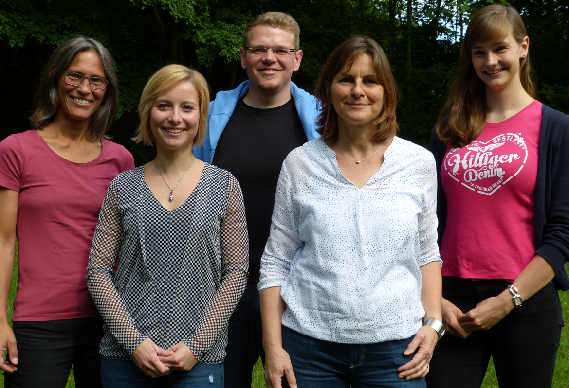 Gruppenfoto, 5 Personen auf einer Wiese vor Bäumen	