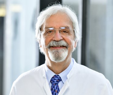 Porträtbild von Michael Gebel, der einen weißen Arztkittel trägt
