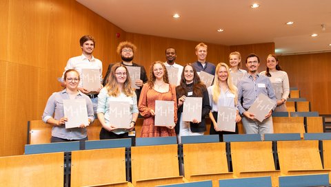 Förderer und Stipendiaten stehen in einem Hörsaal und zeigen ihre Urkunden.