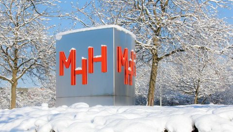 Eine Stele mit dem MHH-Logo, dahinter sind Bäume.