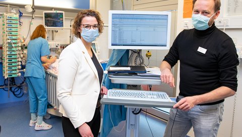 Dr. Antje Wulff und Dr. Thomas Jack stehen neben einem PDMS-Monitor auf der Kinderintensivstation