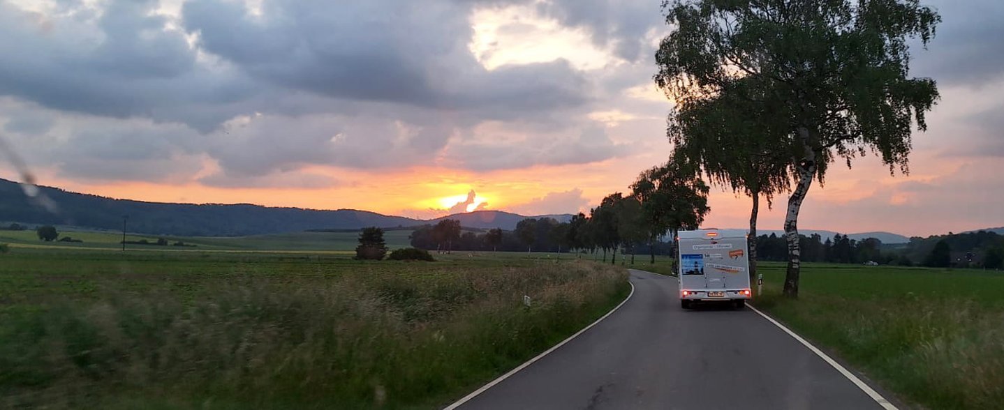 Ein Wohnmobil fährt in den Sonnenuntergang. 